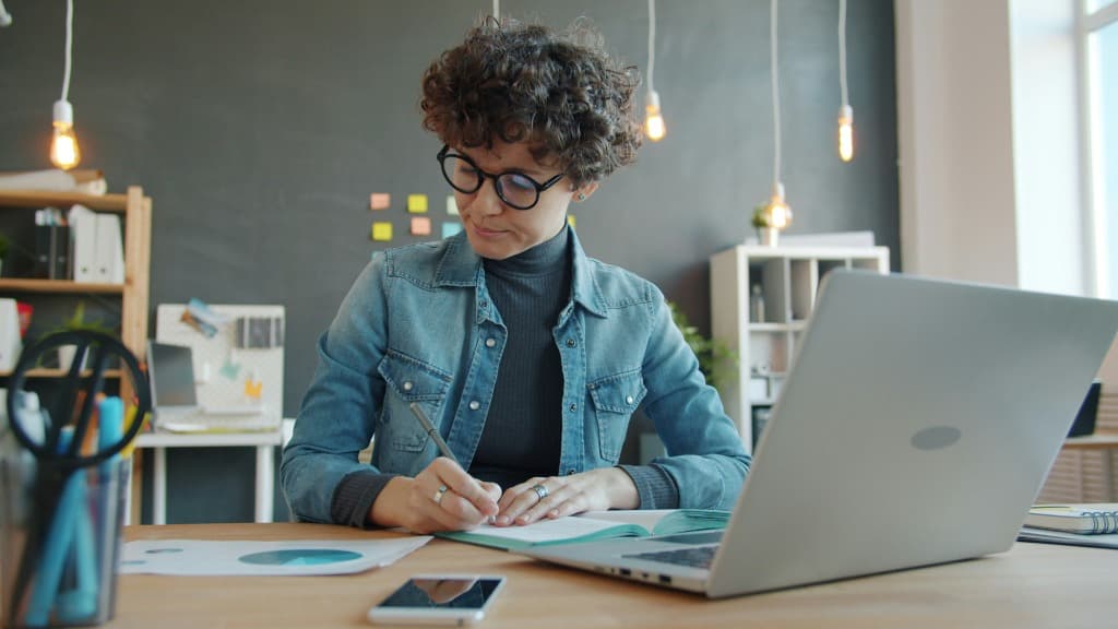 Researcher with glasses working on a laptop at a modern workspace.